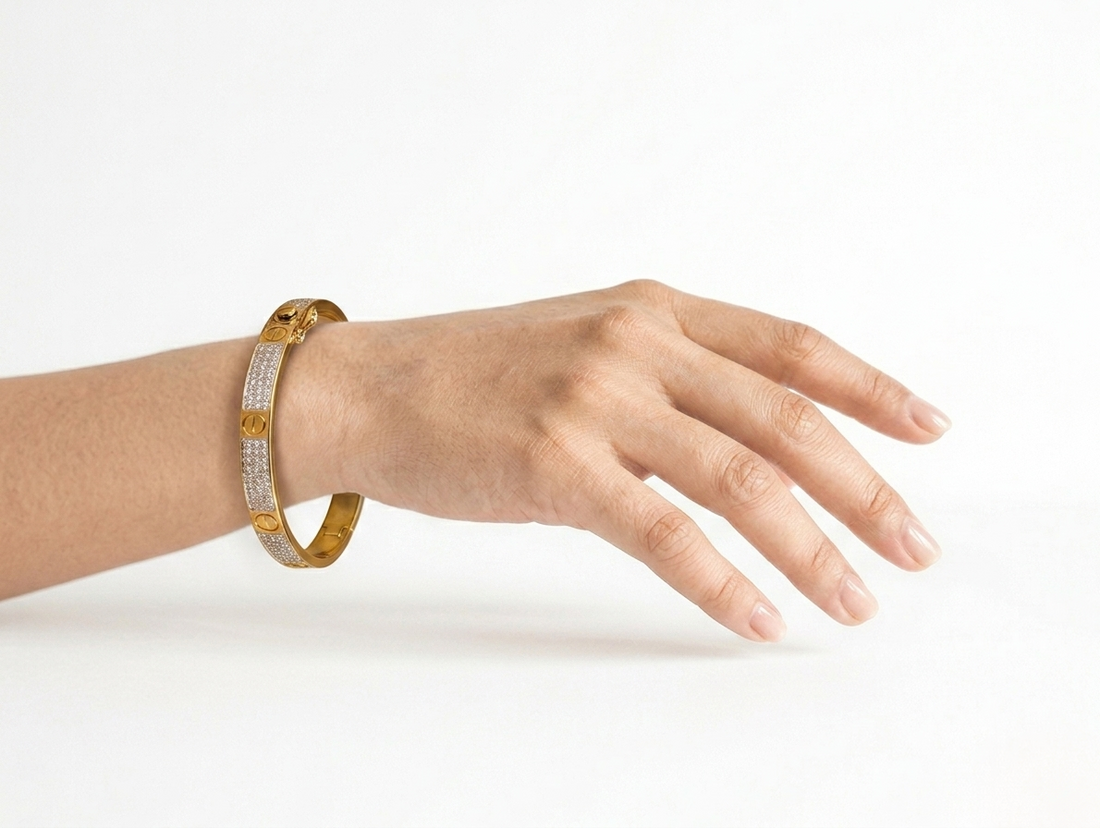 Hand wearing a gold bracelet on a white background